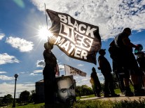 A woman holds a Black Lives Matter flag during an event in remembrance of George Floyd