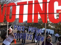 Demonstrators hold signs supporting voting rights